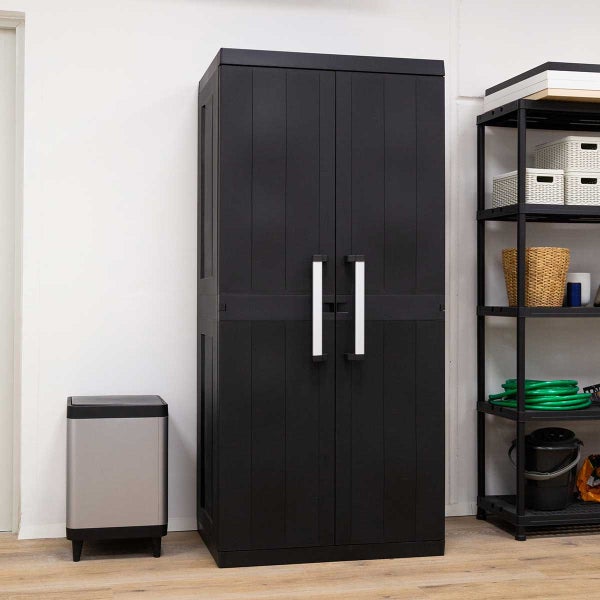 Schwarzer Kunststoff-Schrank mit zwei Türen und langen Griffen in einem organisierten Raum neben einem Regal und einem Mülleimer.