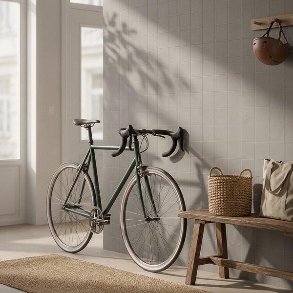 Flur mit einer mit quadratischen Fliesen verkleideten Wand, einem Rennrad, einer Holzbank, einem Korb und einem Fahrradhelm.