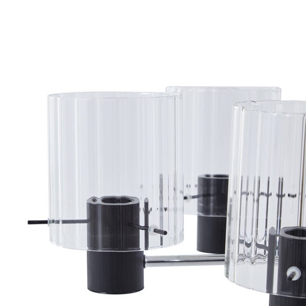 Nahaufnahme einer modernen Deckenleuchte mit zylindrischen Schirmen aus geriffeltem Glas und schwarzen Fassungen an einem Chromgestell.