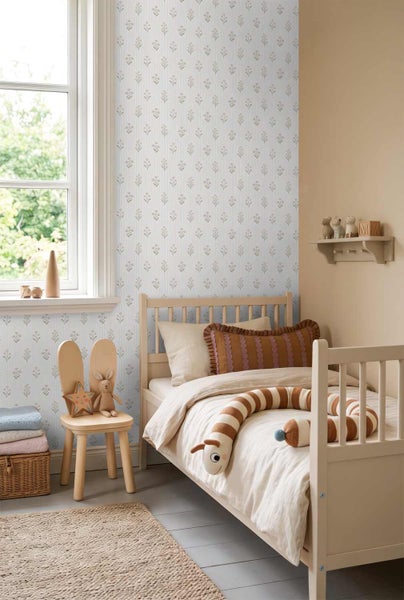 Hell gestaltetes Kinderzimmer mit gemusterter Vliestapete, einem Holzbett und einem Kinderstuhl mit Hasenohren vor einem Fenster.