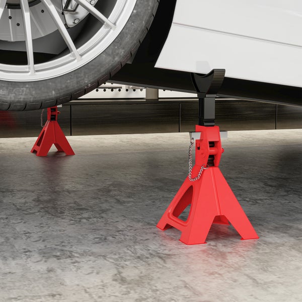 Zwei rote Unterstellböcke stützen ein weißes Fahrzeug auf einem Betonboden in einer Garage.