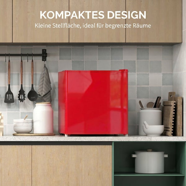 Kleiner roter Kühlschrank auf einer Küchenarbeitsplatte zwischen Küchenutensilien unter Wandschränken.