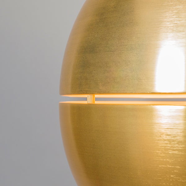 Detailaufnahme einer goldenen Hängelampe mit Lichtspalt