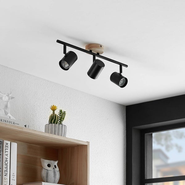 Dreiflammiger Deckenstrahler aus schwarzem Metall mit rundem Holzsockel und verstellbaren zylindrischen Spotköpfen.