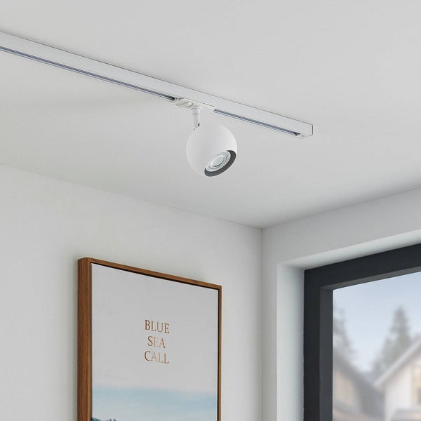 Modernes Schienensystem mit weißem, kugelförmigem Strahler an einer weißen Decke in einem hellen, minimalistischen Raum.