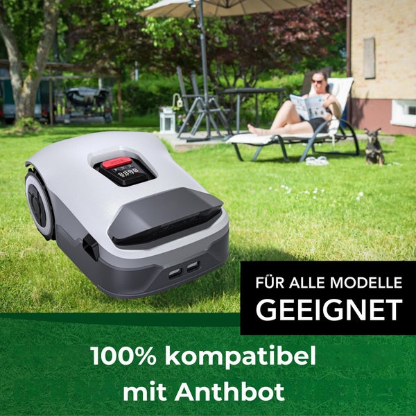 Rasenmähroboter im Garten mit liegender Frau und Hund im Hintergrund