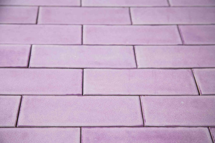 Lila rechteckige Wandfliesen im Mauerverband verlegt mit glänzender Oberfläche.