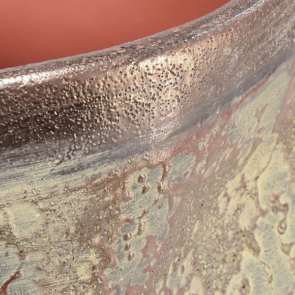 Detailansicht eines strukturierten Pflanzgefäßes mit unebener Oberfläche und metallischem Finish.