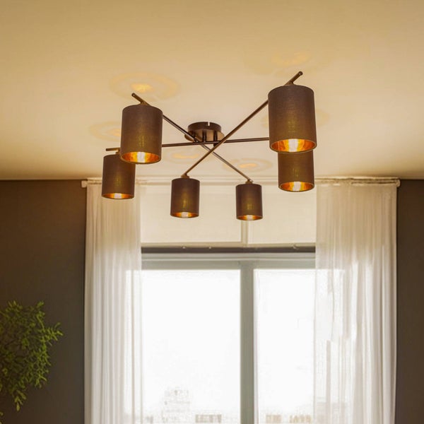Sechsflammige Deckenleuchte mit zylindrischen Stoffschirmen und Metallarmen in einem hellen Raum mit weißen Vorhängen.