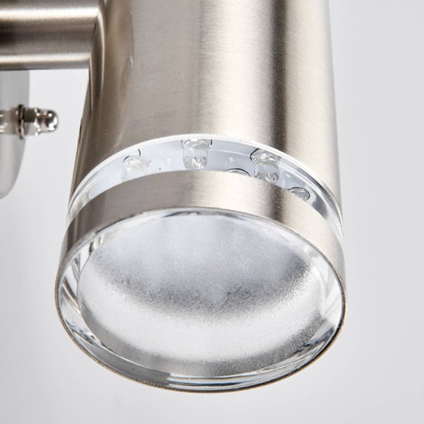 Nahaufnahme einer zylindrischen Wandleuchte aus gebürstetem Metall mit integrierten LED-Leuchtmitteln und einer strukturierten Glaslinse.