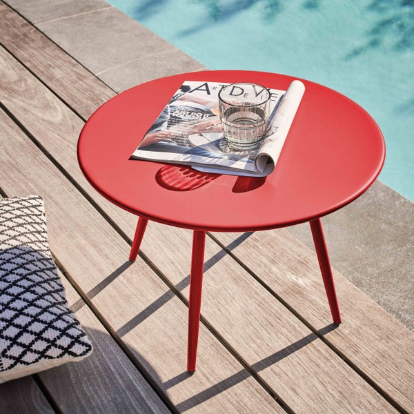 Runder Metall-Beistelltisch auf einer Holzterrasse am Pool mit einer Zeitschrift und einem Wasserglas.