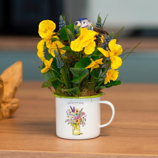 Dekorative Blumenanordnung in einer Tasse mit Vogel-Ornament
