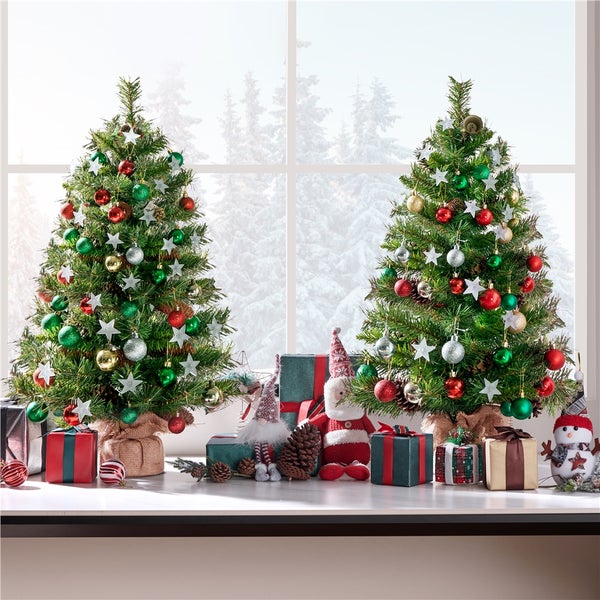 Dekoratives Weihnachtszimmer mit zwei kleinen Weihnachtsbäumen, Geschenken und saisonalen Ornamenten.