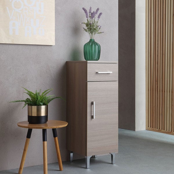 Ein moderner Badschrank mit Schublade und Tür auf Metallfüßen in einem eingerichteten Badezimmer mit Beistelltisch und Pflanze.