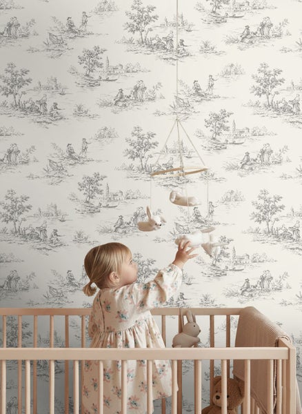 Kinderzimmer mit Babybett und Vliestapete im Toile de Jouy Stil, die pastorale Szenen zeigt.