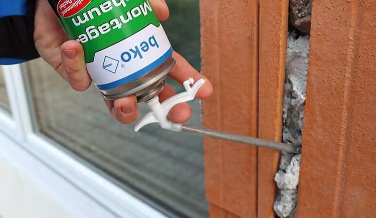 Anwendung von beko Montageschaum mit einem Sprührohr in eine Fuge zwischen Mauerwerk und Fensterrahmen.