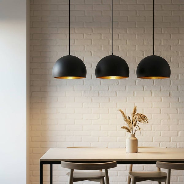 Drei schwarze Hängeleuchten mit goldenem Innenraum über einem Esstisch.