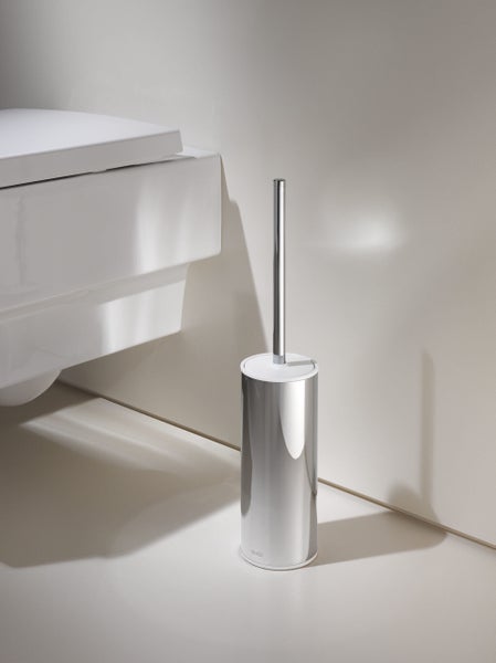 Freistehende WC-Bürstengarnitur aus verchromtem Metall neben einer weißen Toilette in einem modernen Badezimmer.