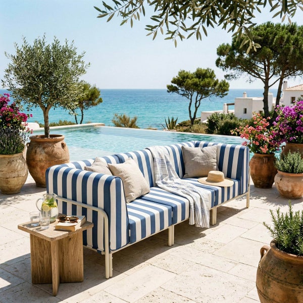 Blau-weiß gestreiftes Outdoor-Lounge-Sofa auf einer hellen Steinterrasse am Pool mit Meerblick und Terrakotta-Pflanzkübeln.