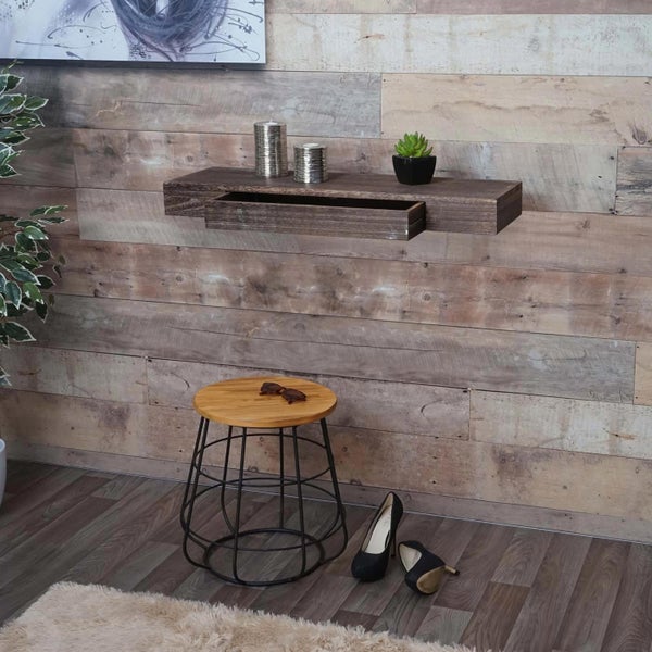 Wohnzimmer-Szene mit Wandregal, Hocker und dekorativen Elementen vor einer Holzwand