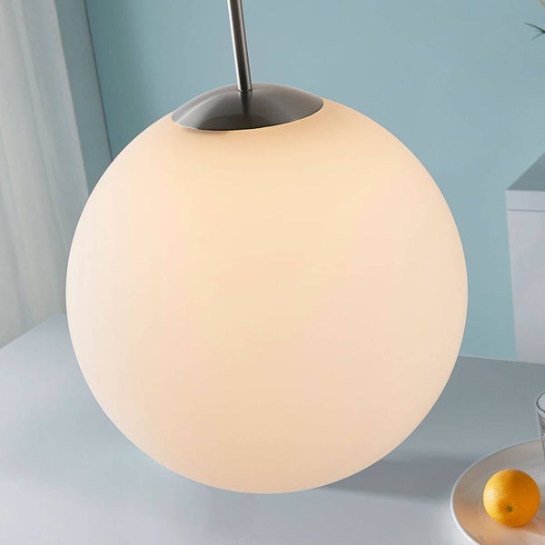 Kugelförmige Pendelleuchte aus Glas mit Metallaufhängung über einem Tisch.