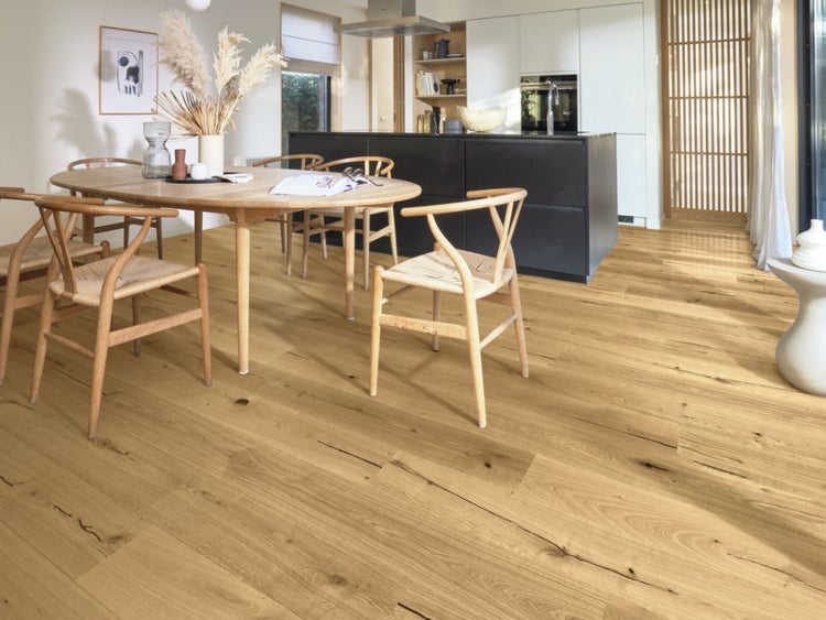 Parkettboden Eiche Landhausdiele in Esszimmer mit Holztisch, Stühlen und einer modernen Kücheninsel im Hintergrund.