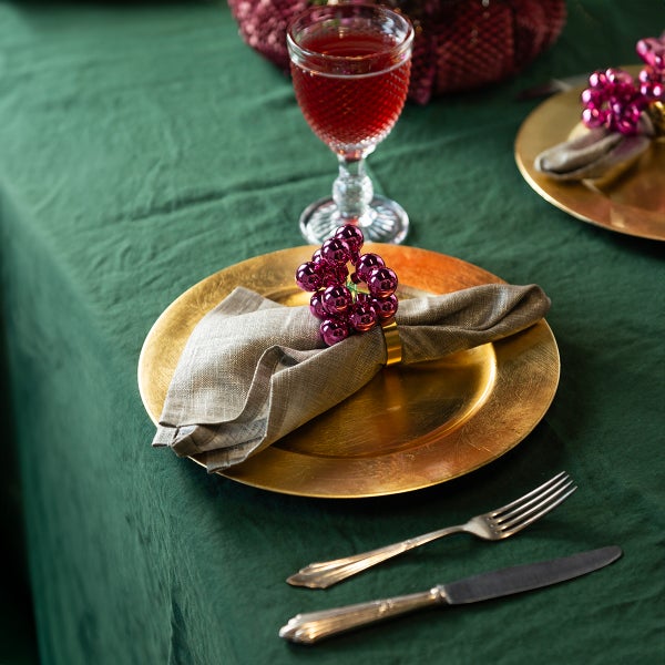 Gedeckter Tisch mit goldenem Teller, Serviette, Serviettenring, Besteck und Glas