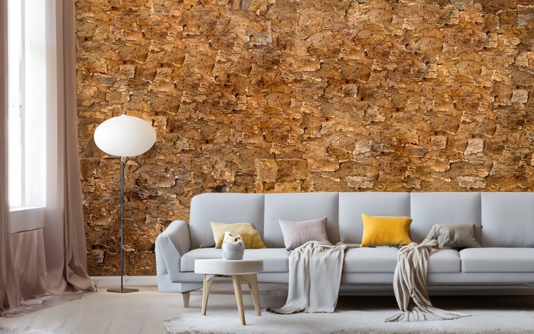 Fototapete in Korkoptik an einer Wand in einem hellen, geräumigen Wohnzimmer mit Sofa, Stehlampe und Vorhängen.