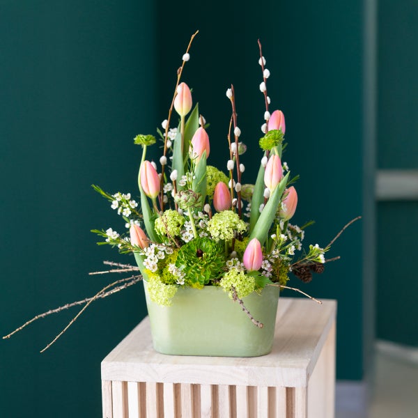 Blumenarrangement mit Tulpen und Zweigen in hellgrünem Gefäß