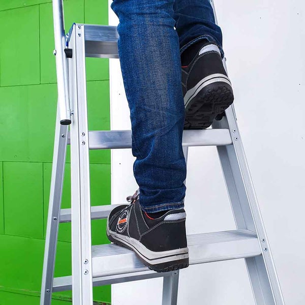 Person steigt auf eine Aluminiumleiter