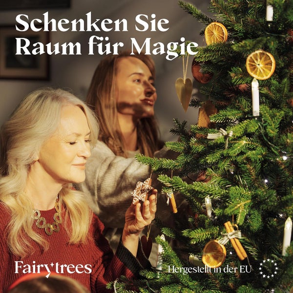 Zwei Frauen schmücken einen künstlichen Weihnachtsbaum mit natürlichen Dekorationen wie Orangenscheiben und Zimtstangen von Fairytrees.