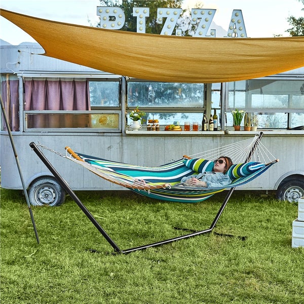 Frau entspannt in einer Hängematte mit Gestell und Sonnensegel vor einem Pizza-Imbisswagen auf einer Wiese