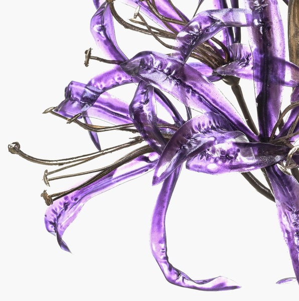 Nahaufnahme einer dekorativen Blume aus Metall und violettem Glas mit geschwungenen Blütenblättern.