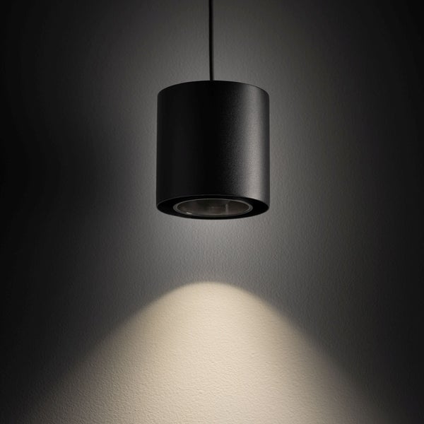 Schwarze zylindrische Pendelleuchte mit einem nach unten gerichteten Lichtkegel.