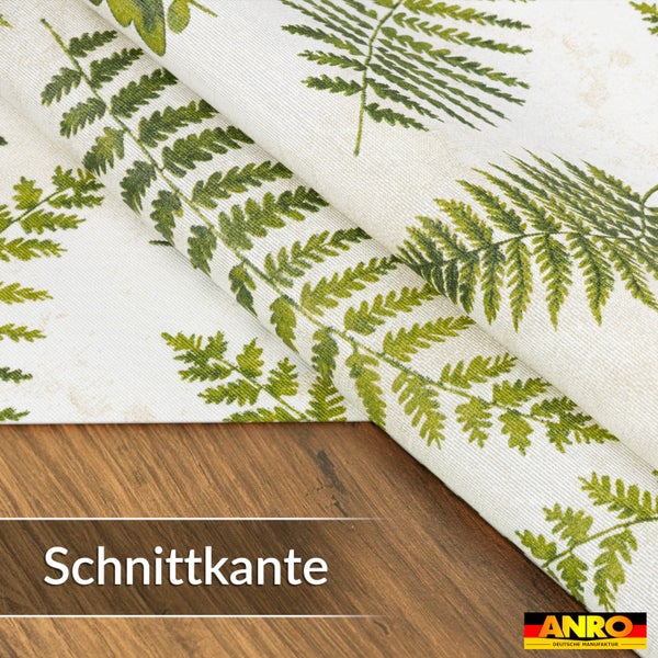Wachstuch mit Farn-Muster an einer Schnittkante auf einer Holzoberfläche. ANRO Deutsche Manufaktur Logo.