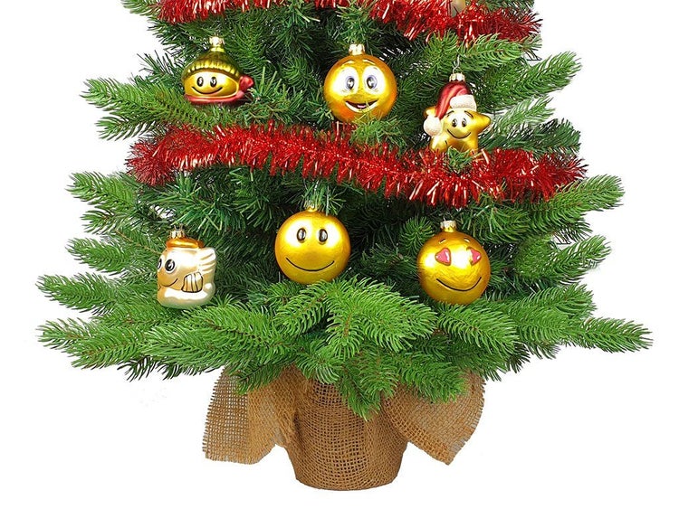 Weihnachtsbaum geschmückt mit lustigen Emoji Christbaumkugeln und Girlande, eingewickelt in Jute