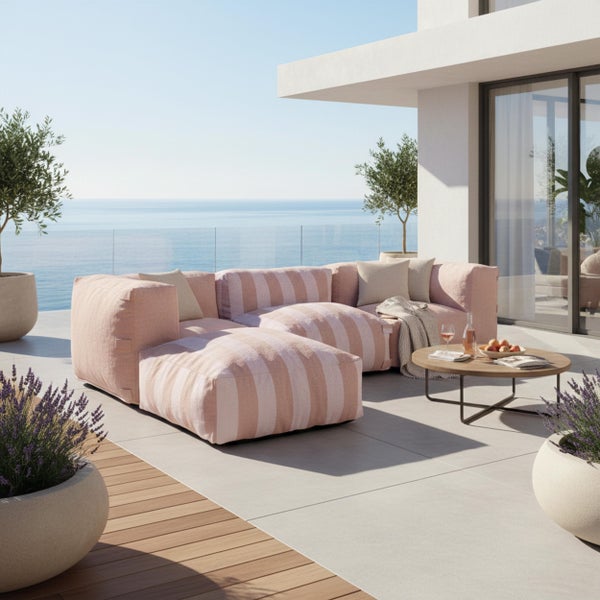 Modernes modulares Lounge Sofa Set mit gestreiften Polstern auf einer hellen Terrasse mit Meerblick und Pflanzgefäßen.