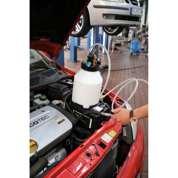 Ein Auto mit offener Motorhaube und einem Bremsenentlüftungsgerät im Motorraum.