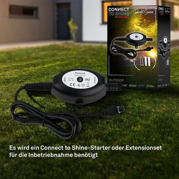 Briloner Connect to Shine Dämmerungssensor für den Außenbereich mit Schutzart IP67, inklusive Anschlusskabel und Verpackung auf einer Rasenfläche.