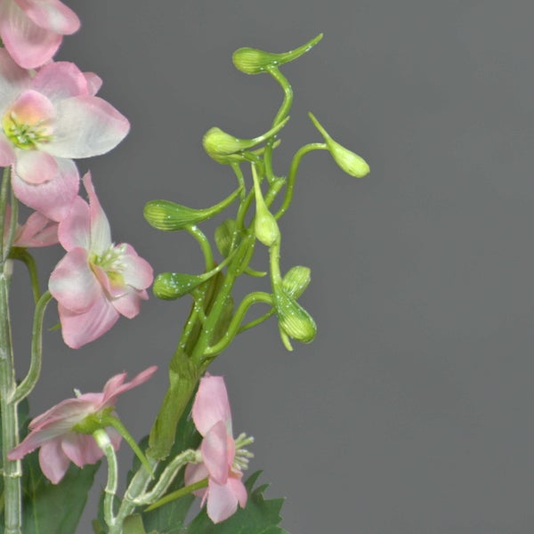Künstlicher pinkfarbener Ritterspornzweig mit grünen Knospen und Blüten.