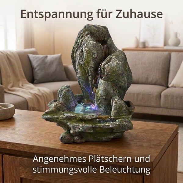 Zimmerbrunnen in Steinoptik mit integrierter LED Beleuchtung auf einem Holztisch in einem Wohnzimmer zur Entspannung