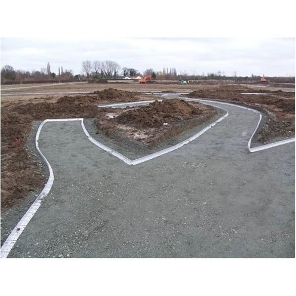 Weitläufige Baustelle mit geschwungener Rasenkante zur Begrenzung eines Schotterwegs auf Erdboden mit Erdhaufen im Hintergrund.