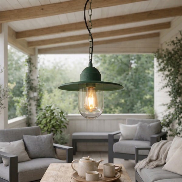 Vintage Außenpendelleuchte mit grünem Metallschirm und Glasabdeckung über einer Terrasse mit grauen Sitzmöbeln und Pflanzen.