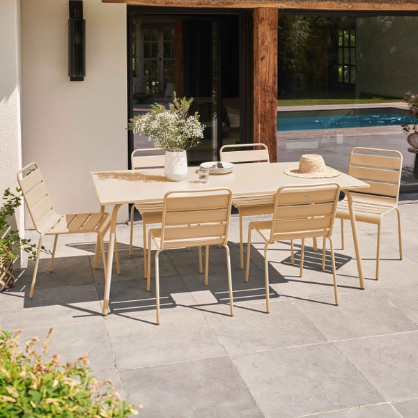 Modernes Gartenmöbel-Set aus Metall mit rechteckigem Tisch und sechs Stapelstühlen in Beige auf einer hellen, organisierten Terrasse.