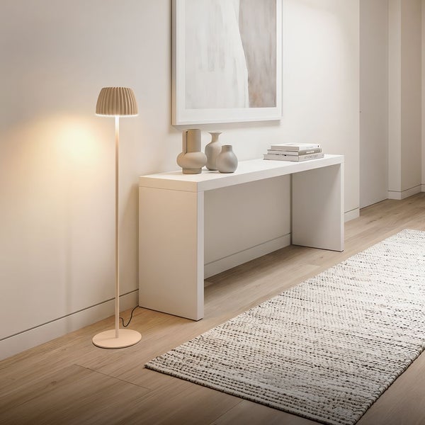 Moderne Stehleuchte mit gefaltetem Schirm in einem hellen, minimalistischen Flur mit Konsolentisch und gewebtem Teppich.