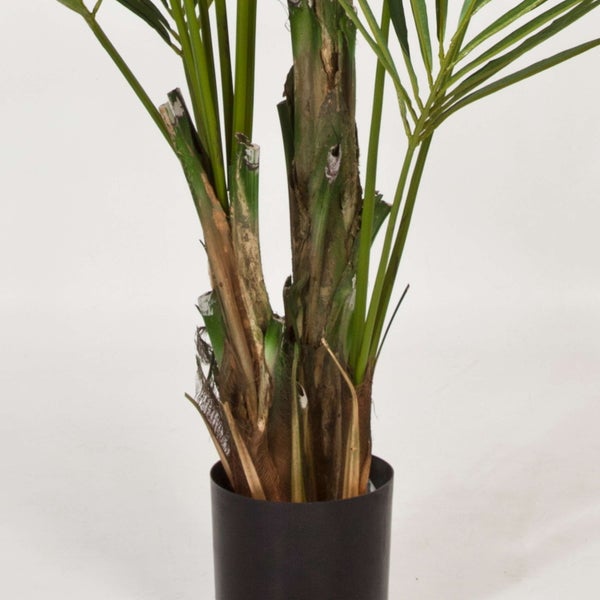 Künstliche Palme im schwarzen Topf, Detailansicht des Stamms und der grünen Blätter.