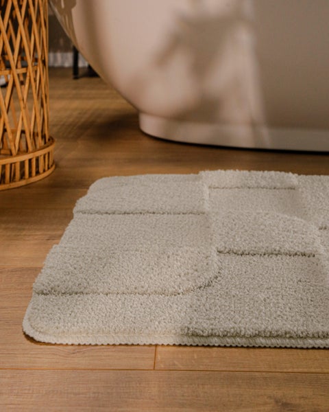 Beige Badematte mit geometrischem Reliefmuster und Detailansicht der weichen Textur.