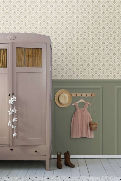 Wohnraum mit gemusterter Tapete, Wandpaneelen in Erdtönen, einem Schrank und einer Garderobe mit Hut und Kinderkleid.
