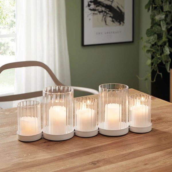 Fünf Windlichter aus Glas und Metall auf einem Tisch