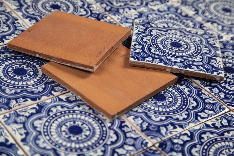 Quadratische Fliesen mit floralem Muster in Blau und unglasierte, braune Fliesen